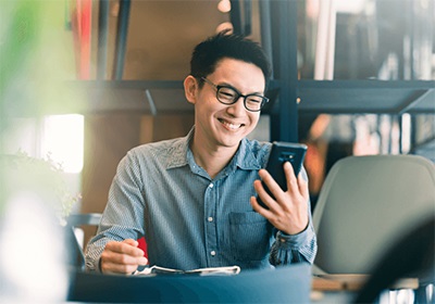 man with glasses smiling and looking at his phone