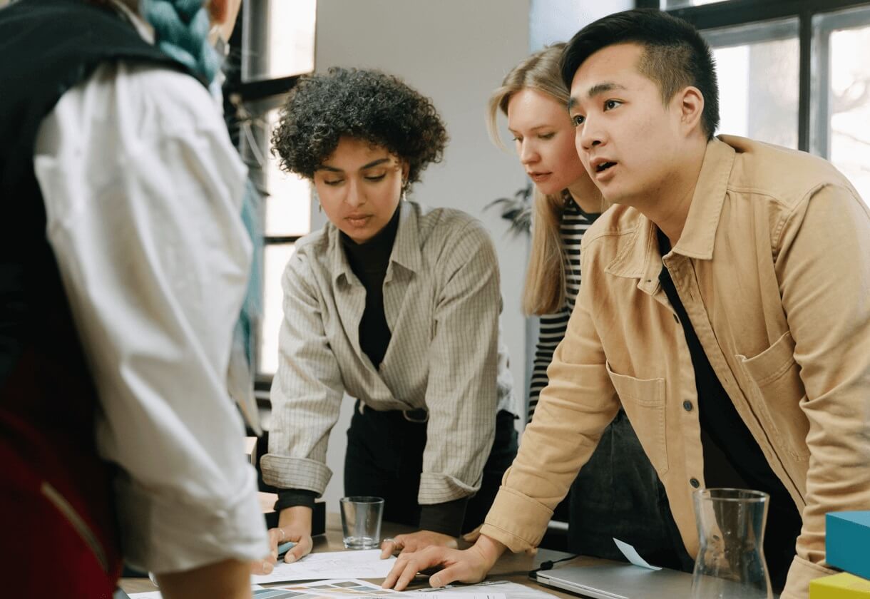 coworkers discussing ideas from paper in office meeting